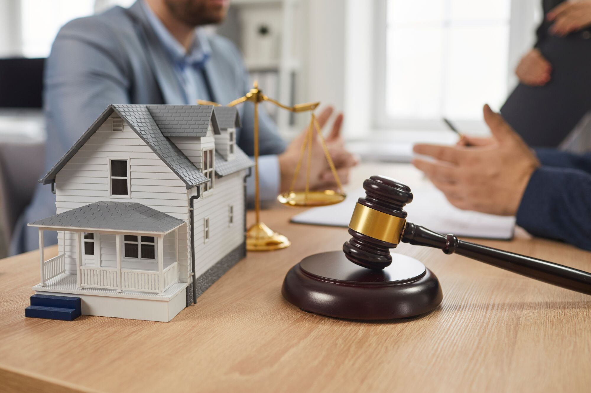 Legal discussions on real estate, featuring a model house, a gavel, and scales of justice, highlighting property law in a lawyer's office.